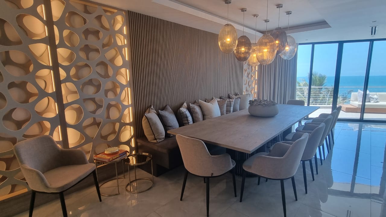 Modern dining toom with a warm atmosphere showcasing its unique wall panelling, custom uphlstery & scatter cushions