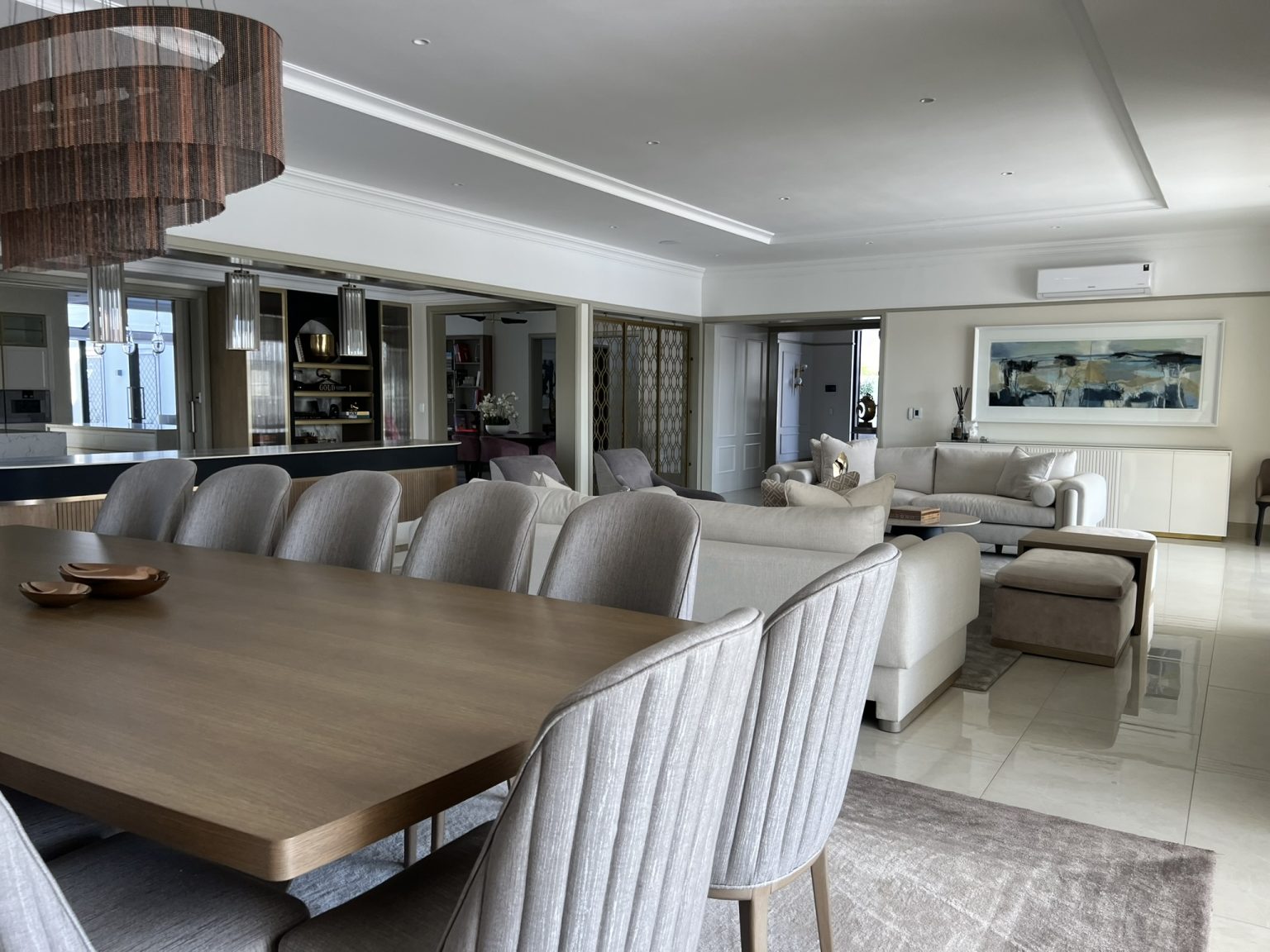 Modern dining room and living room in open space plan with custom grey furniture upholstery and wall frame which puts the room together.